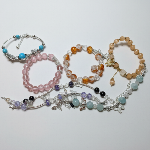 Charm bracelets in pink and amber tones on white background